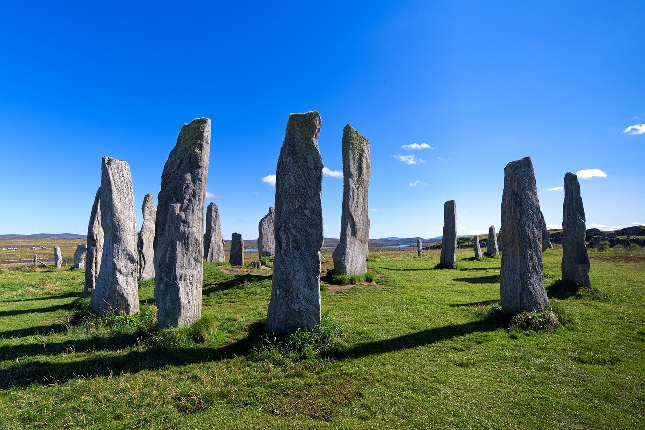 A panoramic shot of the standing stones at sunset, casting long shadows on the ground and creating a mystical atmosphere