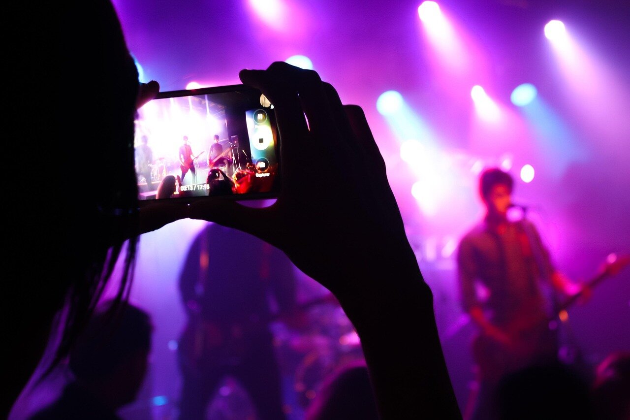 A crowd of music fans gathers outside a concert venue, eagerly discussing the enigmatic singer who has taken the streaming world by storm.
