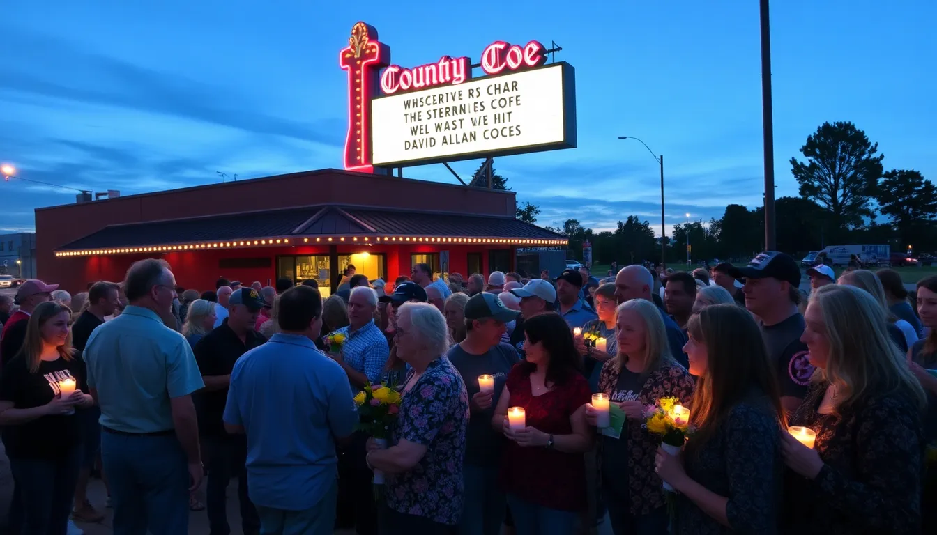 A crowd of fans and musicians gather outside a country music venue, holding candles and flowers in remembrance of David Allan Coe following the announcement of his death.