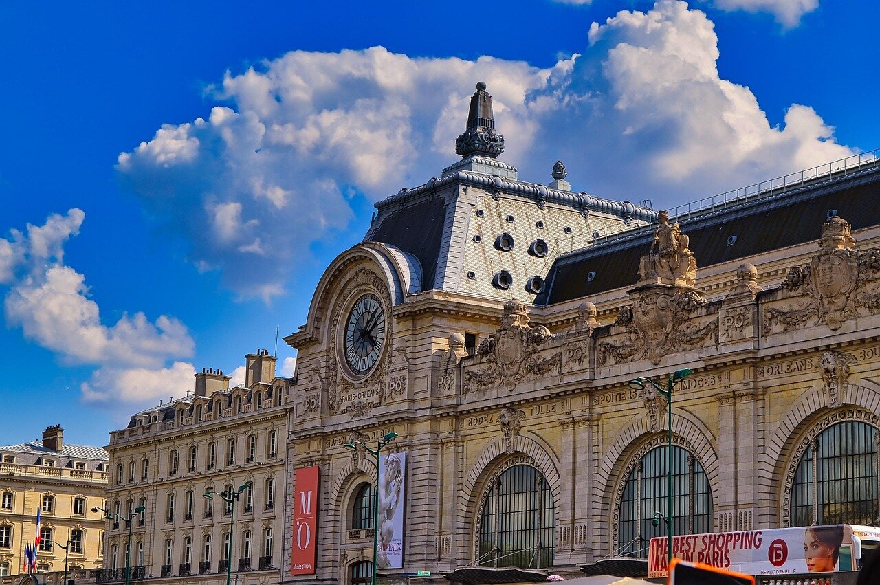 A bustling Paris street is filled with excited fans and gamers holding signs and merchandise in anticipation of the upcoming Esports World Cup.