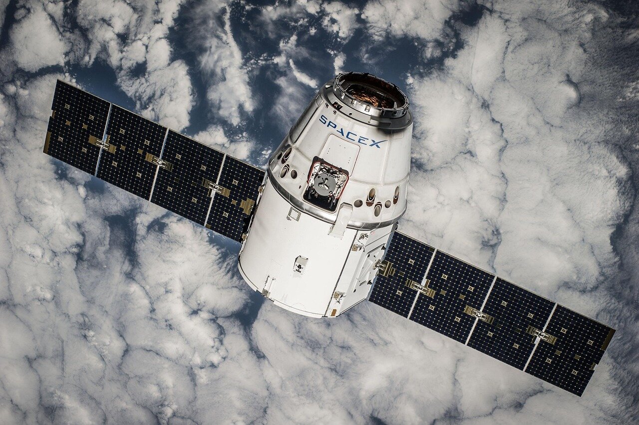 A SpaceX facility is bustling with activity as engineers and technicians prepare for the delayed Starship launch, with various rocket components and equipment visible in the background.