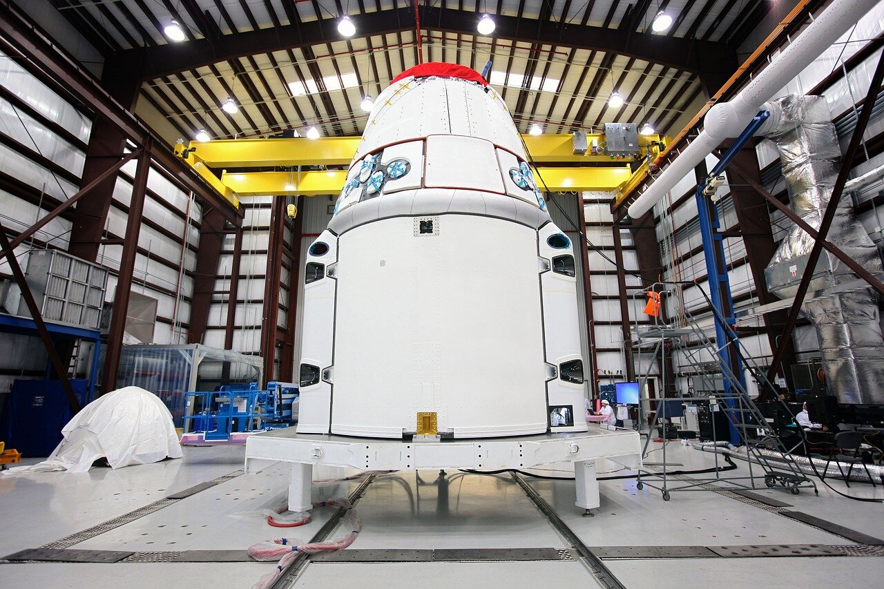 SpaceX's launch pad is empty as the updated Starship rocket stands grounded, surrounded by technicians monitoring equipment amid overcast skies.