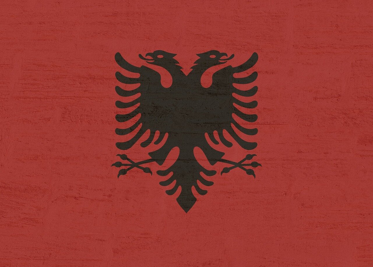 Protesters gather in a city square in Albania, holding signs and chanting against the proposed .6 billion luxury resort backed by Jared Kushner and Donald Trump.
