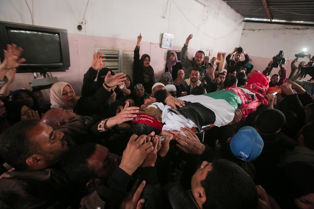 A surgeon operates in a makeshift hospital in Gaza, surrounded by medical staff and injured patients, highlighting the urgent need for healthcare amidst the ongoing conflict.