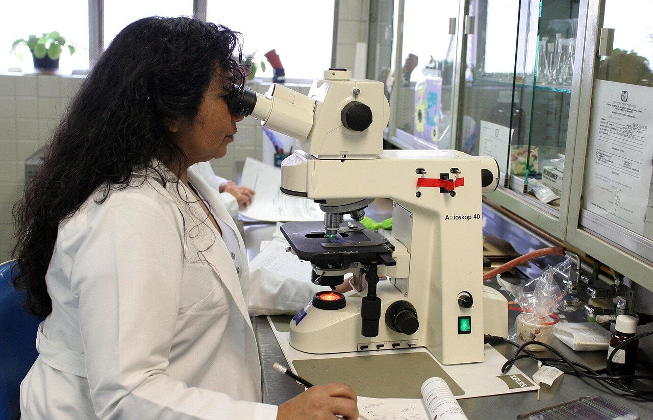 A group of scientists in lab coats discusses research findings on chronic hepatitis B treatment in a modern laboratory setting.