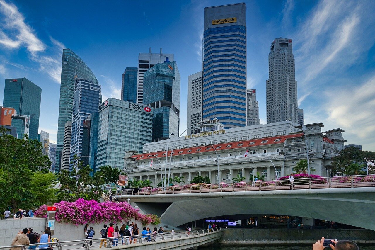 A crowd of moviegoers lines up outside a cinema in Singapore, eagerly waiting to see the Chinese film "The Wandering Earth II" as discussions about cultural identity fill the air.