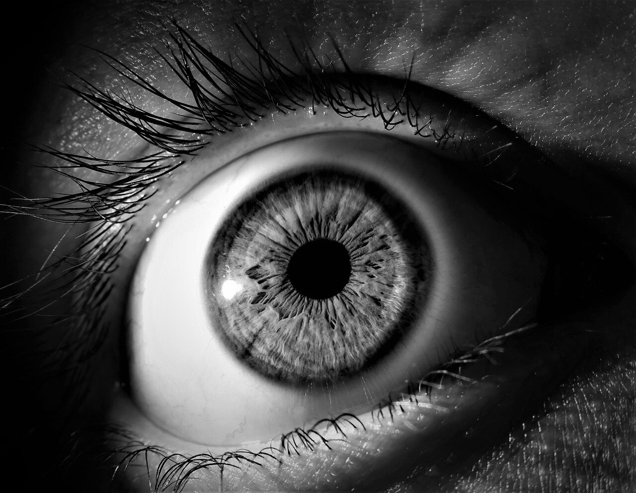 A person rubs their eyes while sitting at a desk cluttered with digital devices, highlighting the impact of prolonged screen time on eye health.
