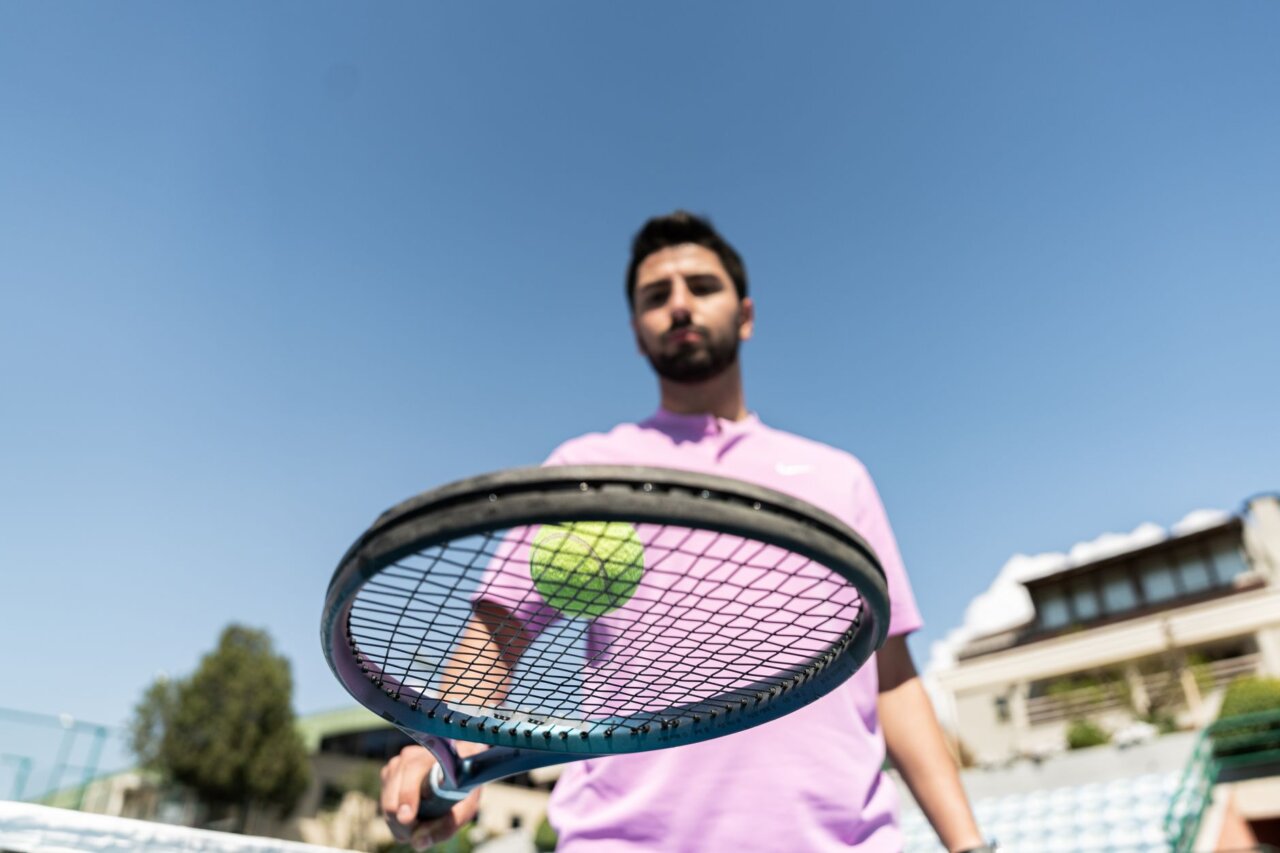 A closeup of Djokovic's intense concentration as he prepares for a serve, reflecting his experience and strategic mindset on the court