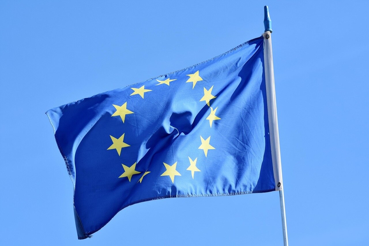 Travelers at a busy airport checkpoint in the EU are seen waiting in line as border officials conduct biometric checks, highlighting the new regulations aimed at enhancing security and managing migration.